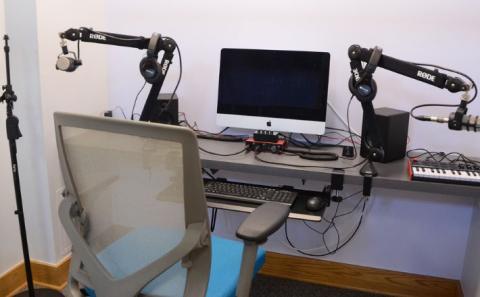 An audio recording and editing suite with microphones, microphone jacks, and an iMac 