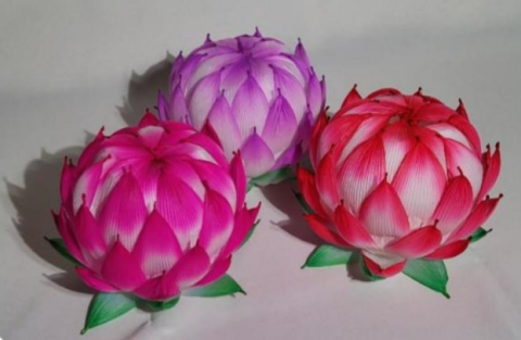 Three lanterns with colorful flower petals over a paper and metal frame