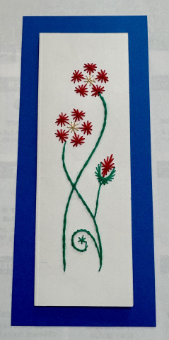 A pin embroidery bookmark featuring long-stemmed red flowers and a flower bud