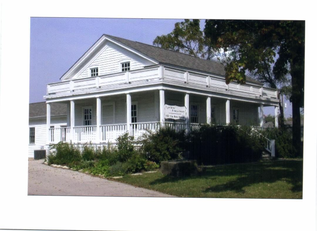 Bliss House two story white wooden structure with wraparound porch and shrubs 