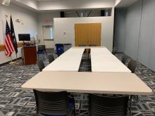Room A with tables arranged in large rectangle with chairs around outside edge; up to 12 people.