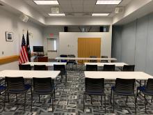 Room A with tables arranged in rows with chairs on one side facing front of room; up to 36 people at 10 tables.
