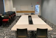 Room B with tables arranged in large rectangle with chairs around outside edge; up to 12 people.
